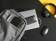 Gray textile urban backpack with laptop, external battery, phone, headphones, mouse and pen on black and yellow background. Travel, trip, study and lifestyle with gadgets. Recharging devices. Close-up