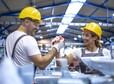 Factory workers greeting each other at production line.