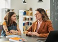 Portrait of caring female teacher talking to girl with disability during consultation in school library
